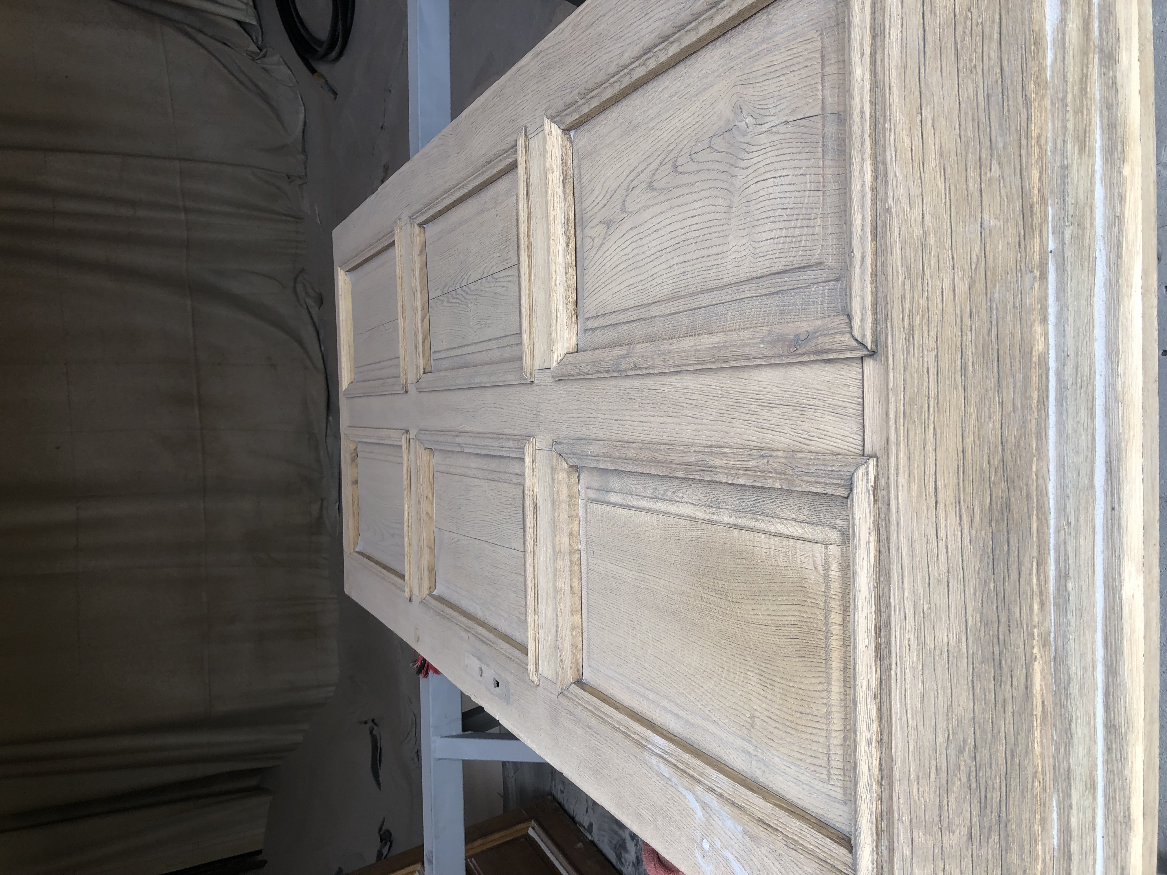 mężczyzna w ciemnym kombinezonie ochronnym używa piaskarki na zardzewiałej stali